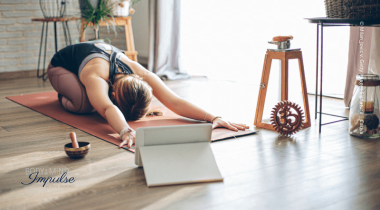 Frau übt Yoga per Online-Kurs am Tablett.